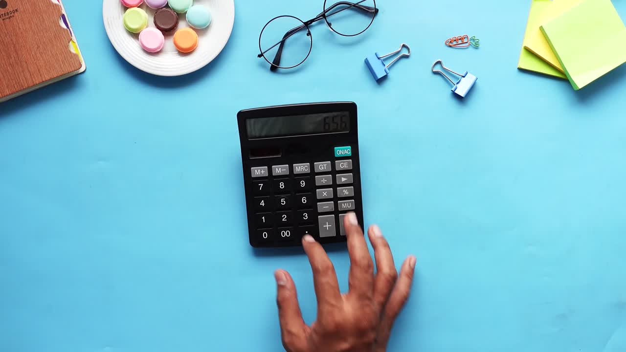 persona que utiliza una calculadora en un escritorio con varios suministros de oficina
