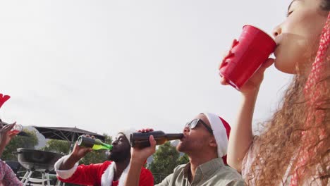 Fröhliche-Gruppe-Verschiedener-Freunde,-Die-Bei-Der-Weihnachtsfeier-Im-Garten-Bier-Trinken