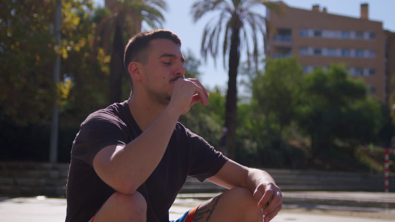 스페인 바르셀로나의 거리 법원에서 에너지 바를 먹고 휴식을 취하는 젊은 백인 남자의 중간 샷