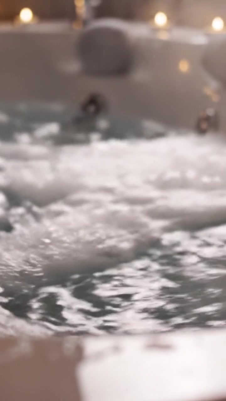Soothing Water Bubbles in a Relaxing Spa Bath, Capturing the Essence of Tranquility and Comfort as Soft Light Reflects off the Surface from Candles Nearby