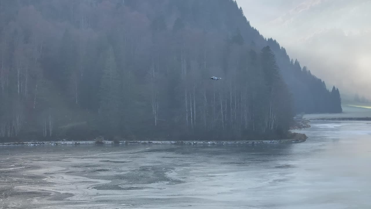 오버시, 나펠스, 글라루스, 스위스에서 안개 숲과 먼 산으로 둘러싸인 부분적으로 얼어붙은 호수, 외로운 드론 실루은 탐험과 현대성의 느낌을 더합니다.