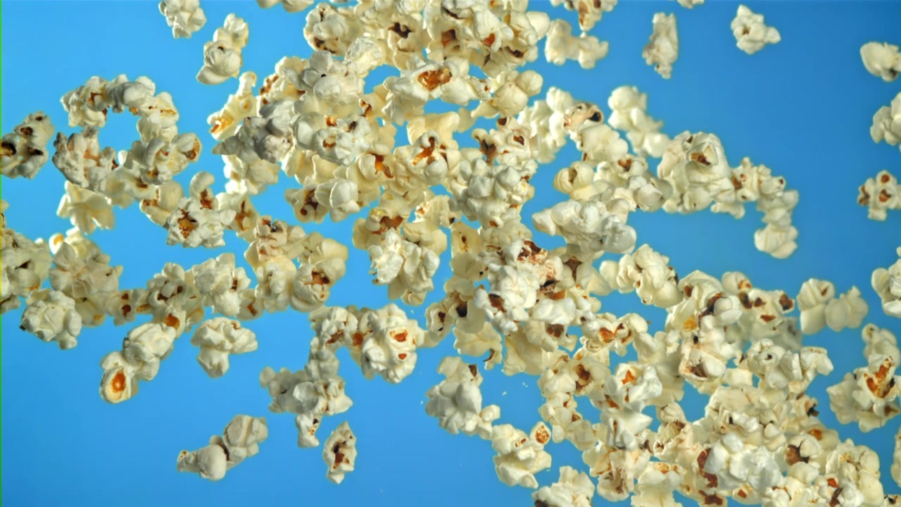 Popkorn som flyr i sakte film mot en blå bakgrunn