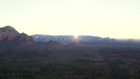 first light cresting over mountains creating sun star flare in morning in sedona