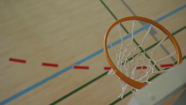 Vista dall'alto di un giocatore di basket maschio afroamericano che segna un canestro contro giocatori di diversa etnia.