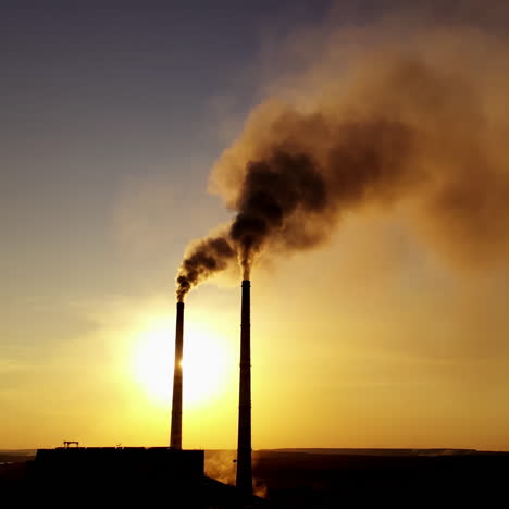 dark silhouette of a factory at sunset. pipes with dirty smoke of metallurgical plant in the evening.