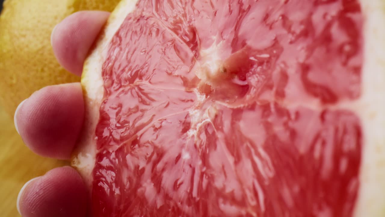 macro video de la mano exprimir el jugo de pomelo