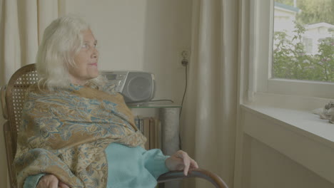 primer plano de una anciana sentada en una mecedora y mirando hacia arriba con una sonrisa