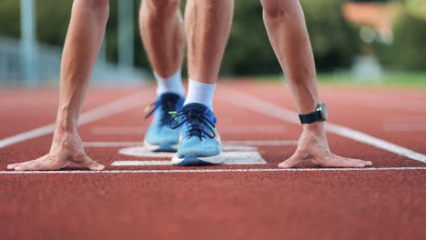 close-up pan shot of runner at the starting position of running track