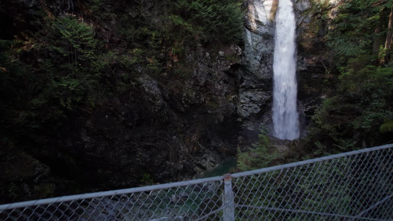 volando sobre el puente colgante para revelar una hermosa cascada forestal