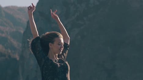 woman-in-dress-raises-hands-against-mountains-slow-motion