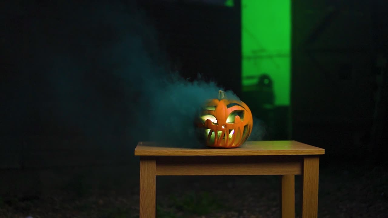 humo azul oscuro que sale de una calabaza tallada con luz interior que parece espeluznante en cámara lenta