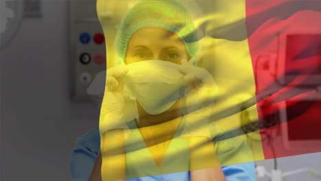 Animation-of-waving-belgium-flag-over-caucasian-female-surgeon-wearing-surgical-mask-at-hospital