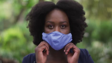 mujer afroamericana poniendo una máscara facial en el parque