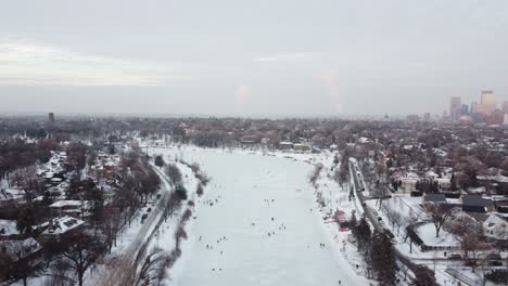 drone over ice skaters on lake of the isles in minneapolis, mn with skyline in background