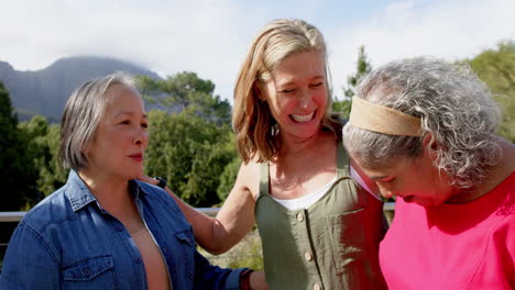 senior biracial woman shares a laugh with asian and caucasian friends outdoors