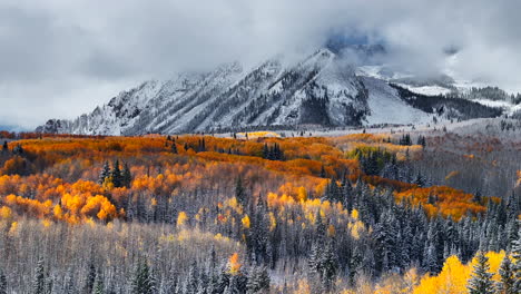 dramático paso kebler crested butte colorado impresionante otoño invierno primeras estaciones de nieve chocan aéreo cinematográfico dron árbol de abeto amarillo bosque montañas rocosas nubes de niebla levantando hacia arriba movimiento jib