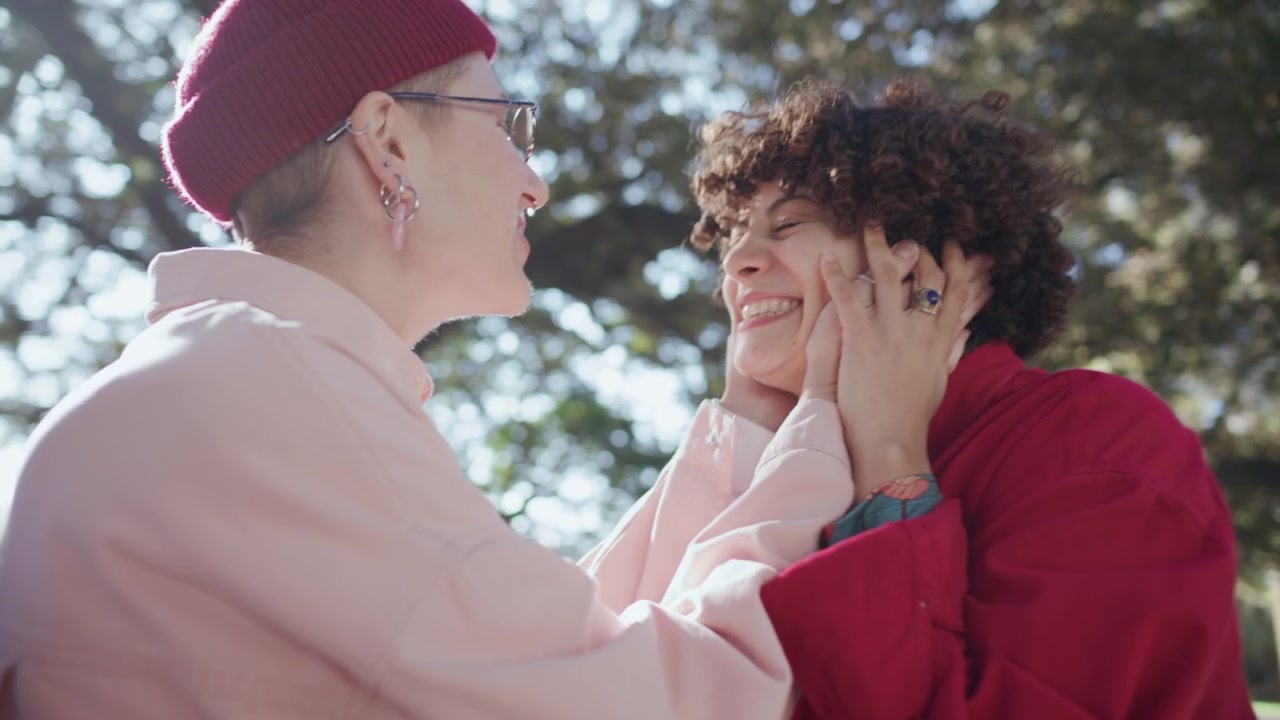 Amiche felici che si abbracciano, sorridono e chiacchierano al parco