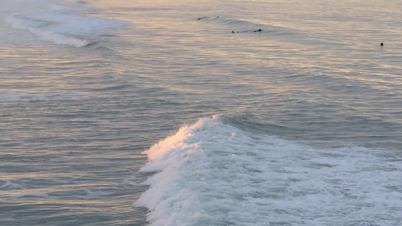 Setting sun falls onto incoming wave as beautiful golden hour colors appear at Pegasus Bay, New Zealand