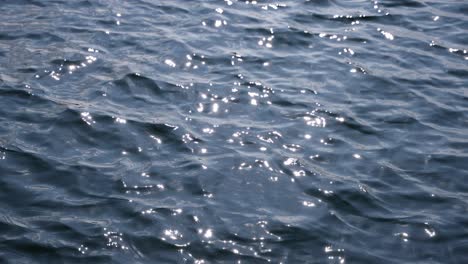 The-shot-of-wavy-water-surface-of-lake-with-sun-reflection,-the-shot-goes-of-focus