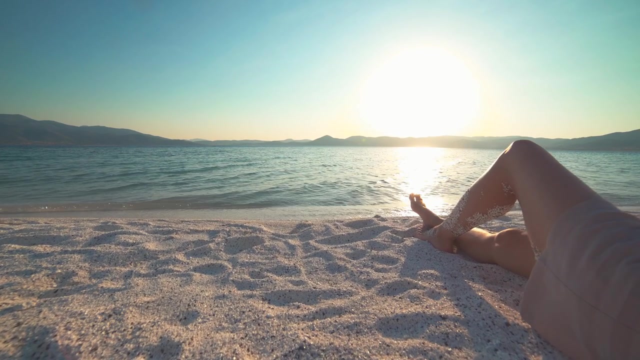 Persona relajándose en una playa de arena al atardecer