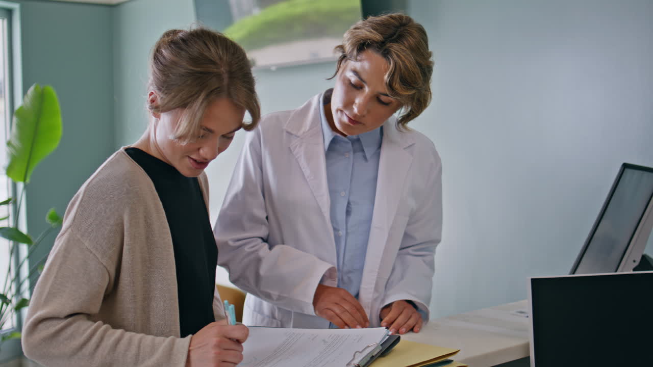 Healthcare worker giving documents to sign to woman patient in clinic closeup