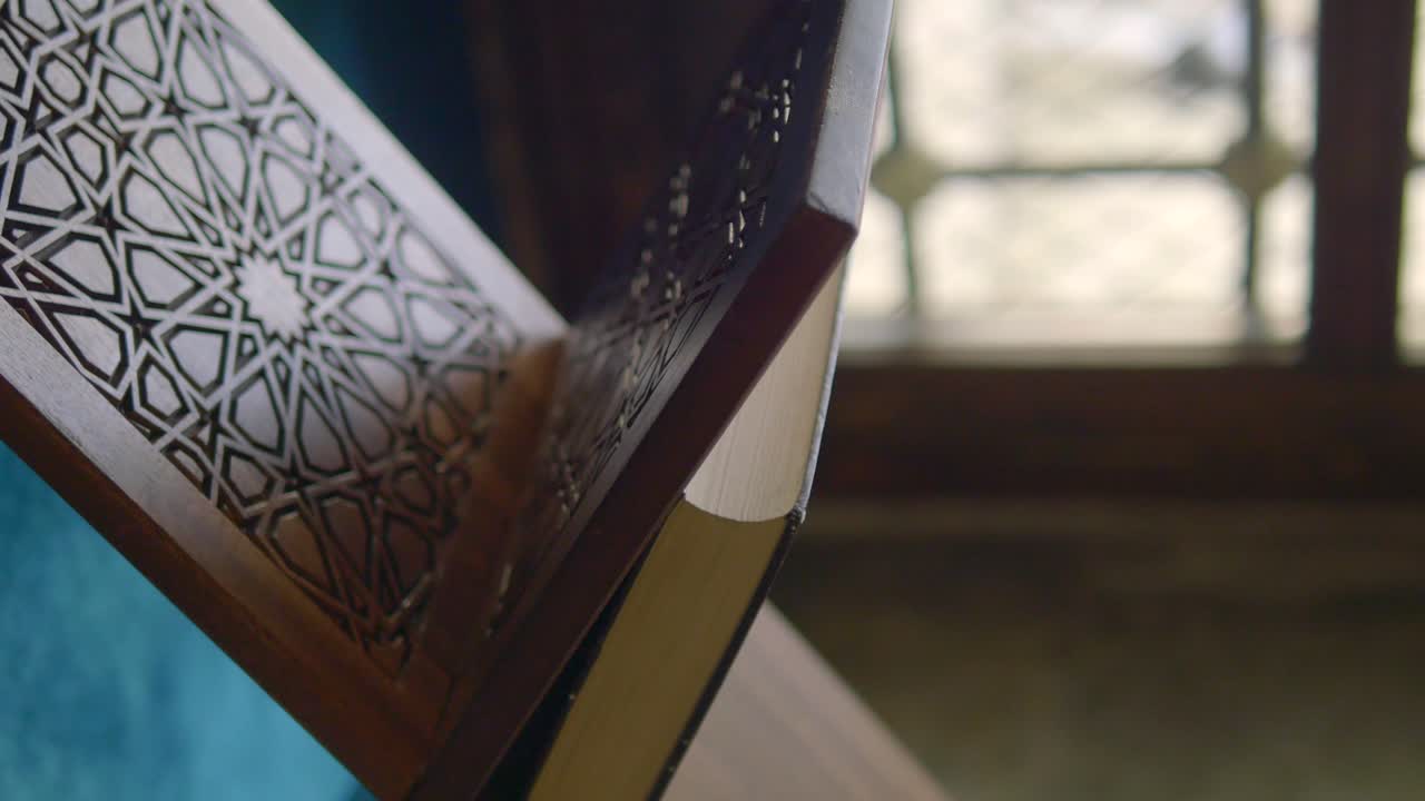 A close-up of the Quran on a wooden stand