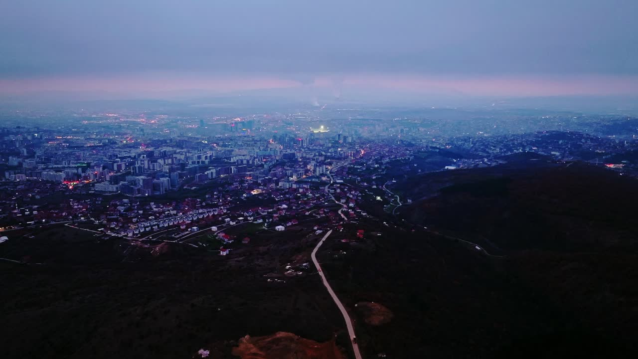 Urban lights shimmer across Pristina’s evening skyline as night slowly sets in