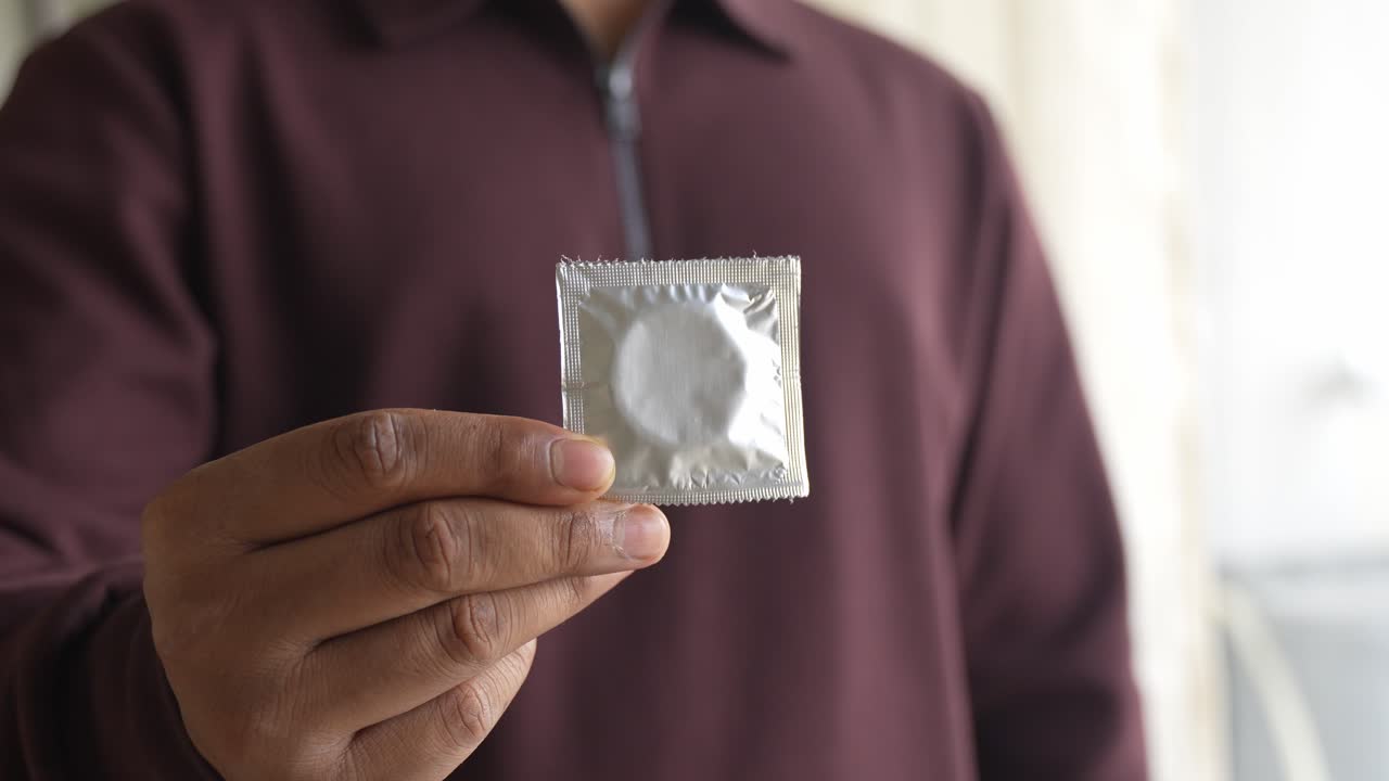 Showing packets of condoms held on finger