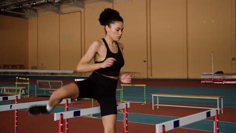 female athlete jumping hurdles