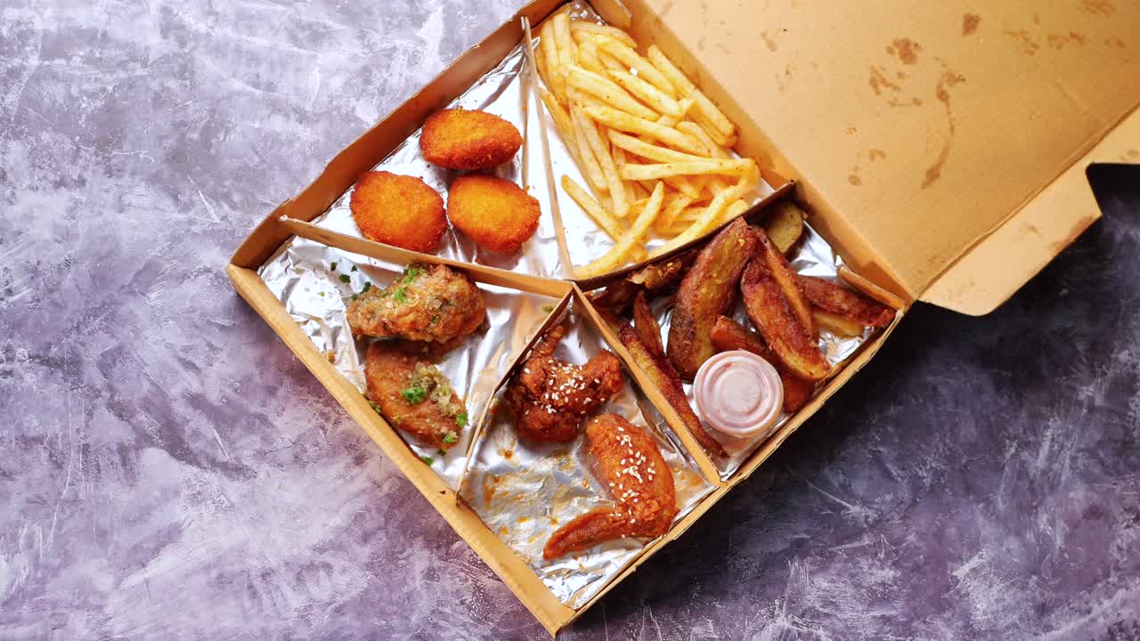 caja de comida con alas de pollo, papas fritas y nuggets