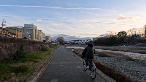 cyclist riding on a path by a river at dusk