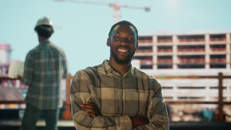 smiling engineer or worker at a bustling construction site with a team