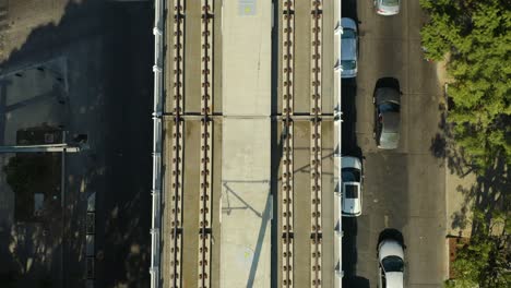 top down aerial view of elevated train tracks over urban street with cars, empty