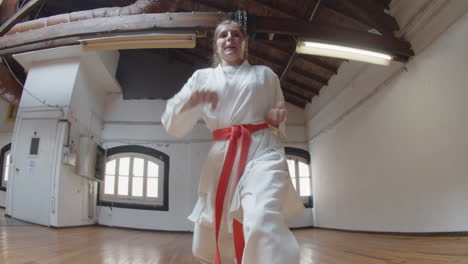 handheld of concentrated girl showing karate beats in gym