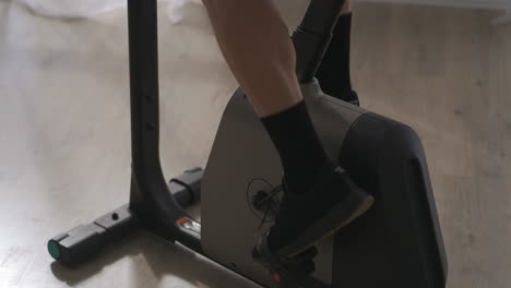 male legs on pedals during training on stationary bike closeup shot healthy lifestyle and fitness at home or gym