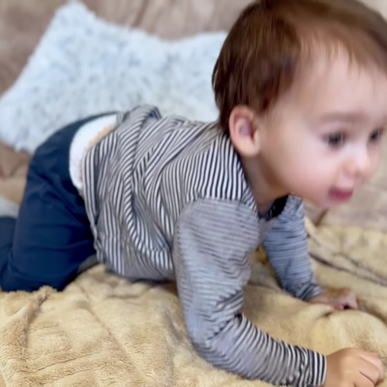 Energetic little Caucasian toddler jumping on the sofa. Happy active baby boy having fun at home