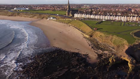 drone revealing scenic landscape of tynemouth longsands beach with waves, beach and tynemouth town