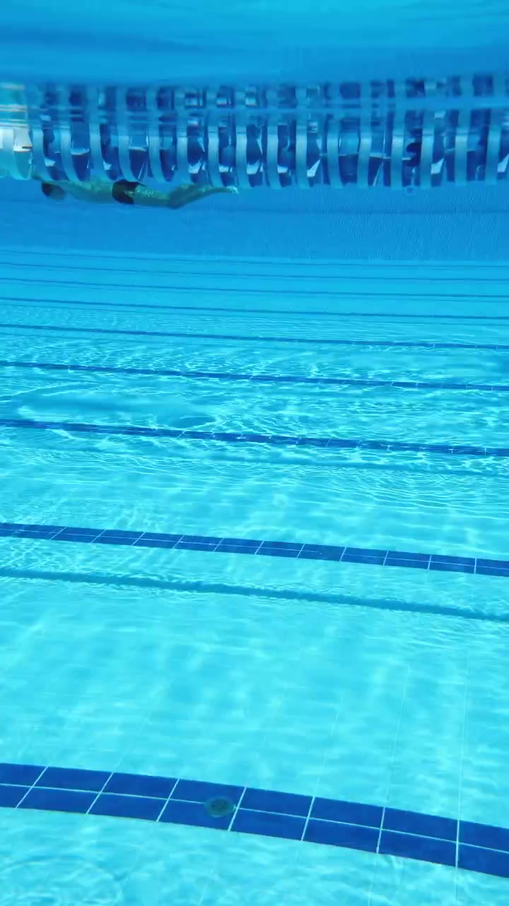 青い反射がある空の屋内プールコースの水中ビュー