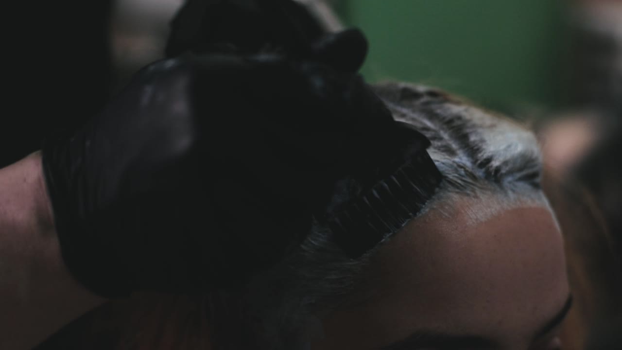 Parrucchiere che Applica la Tinta sui Capelli di una Persona in un Salone di Parrucchieri