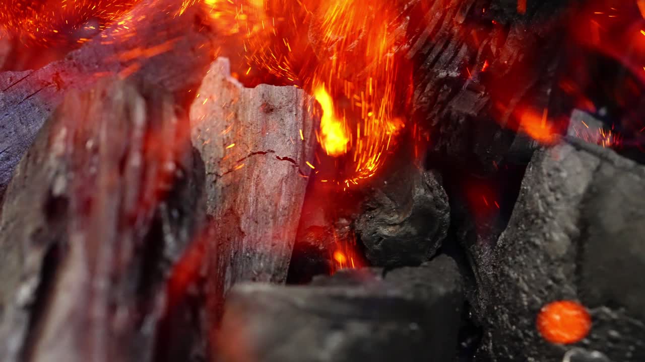 Burning charcoal, glowing embers with crackling heat and fiery sparks flying