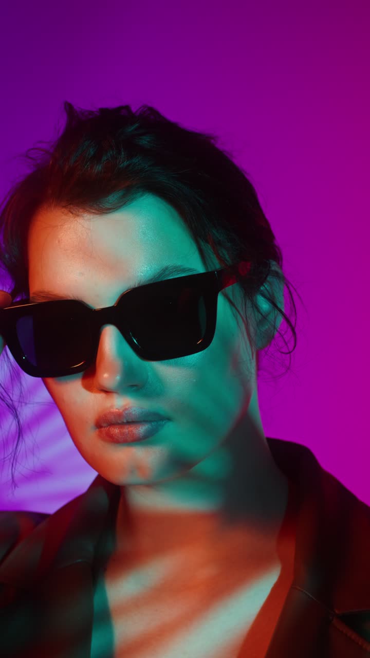 Stylish woman wearing sunglasses in neon light