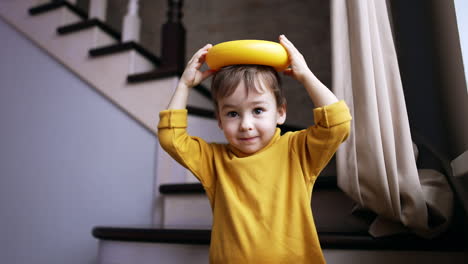 adorable caucasian baby puts the pyramid piece on his head. toy falls down and kid smiles happily.