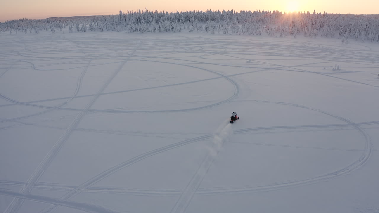 tiro de drone de una moto de nieve en un área abierta de nieve en el bosque durante una fría temporada de invierno en suecia