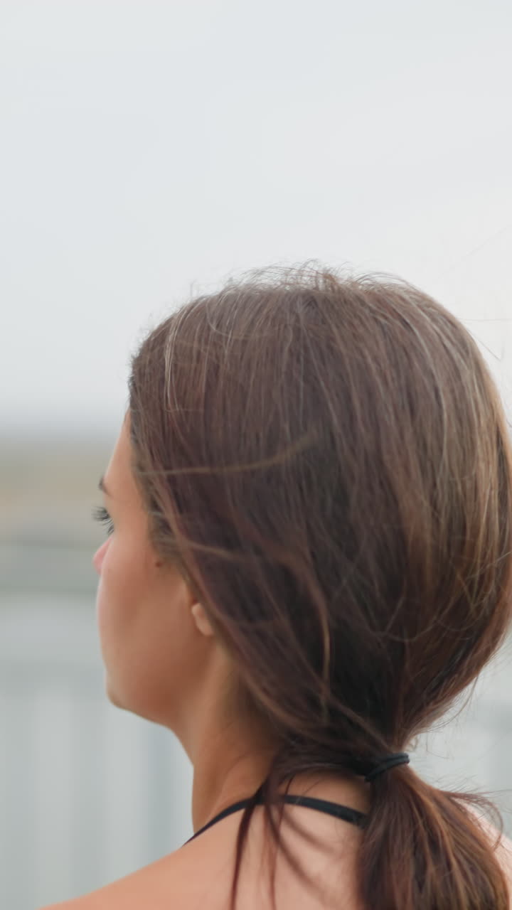 Closeup of a woman jogging with her hair neatly tied, running past an iron fence, the background features a blurred view of the fence, enhancing the focus on the runner s determination and motion