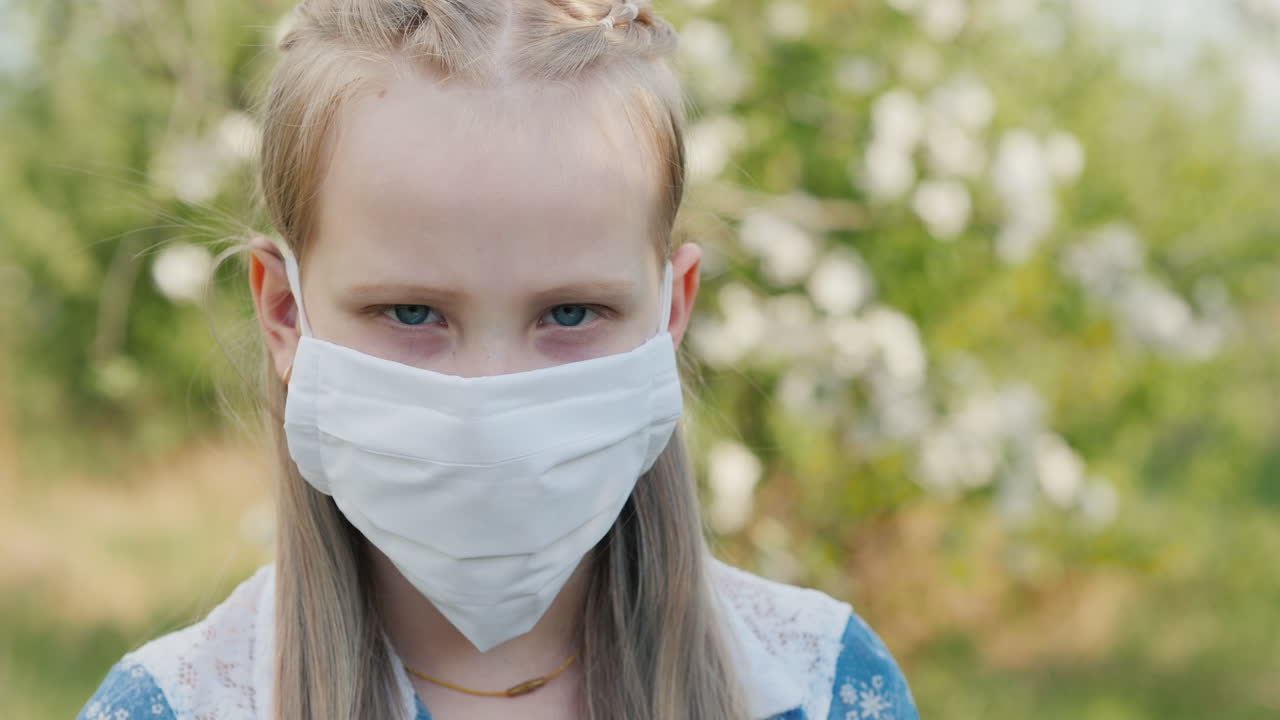 정원에 있는 푸른 나무의 배경에 흰색 보호 마스크를 쓴 아이의 초상화