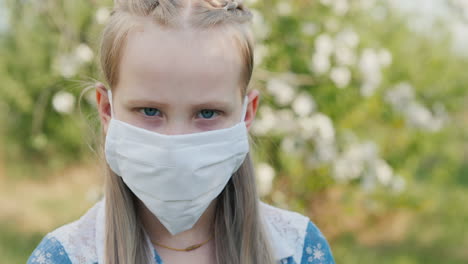Portrait-Of-A-Child-In-A-White-Protective-Mask-Against-The-Background-Of-Green-Trees-In-The-Garden