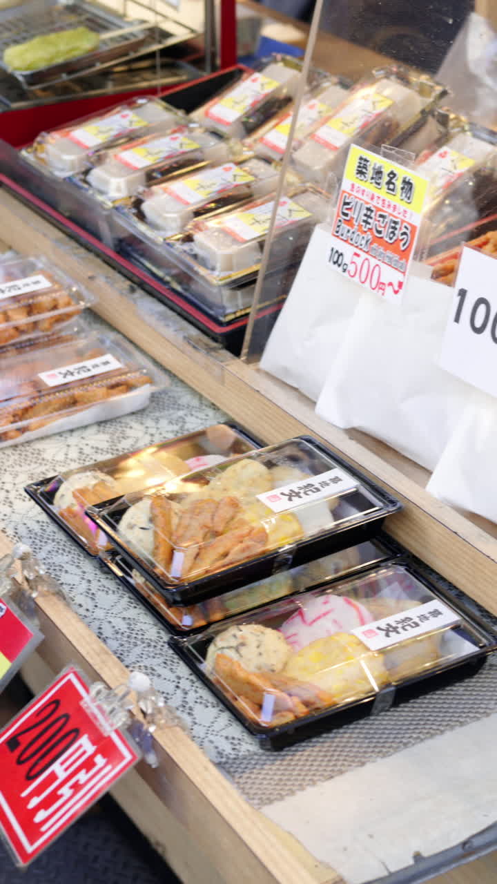 Different types of fried seafood in plastic containers for sale at the Tsukiji Fish Market in Japan. Vertical. Translation: "Produce descriptions"
