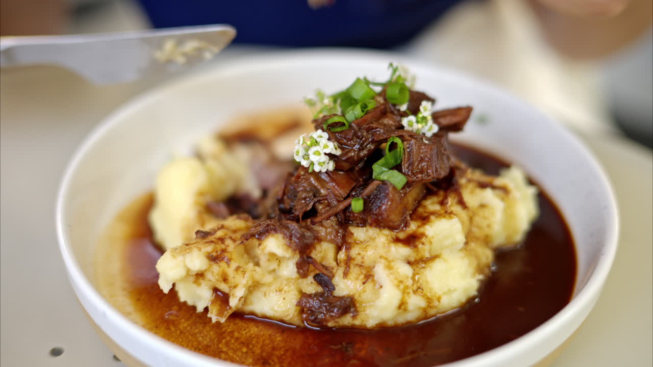 Woman eating pork ribs with smashed potatoes at a restaurant