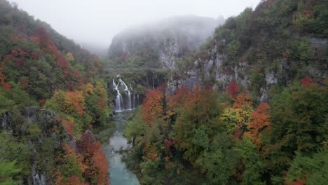 Soaring-through-misty-Plitvice-waterfall-valley,-revealing-scenic-cascades,-aerial
