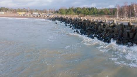 Luftaufnahme-Des-Betonpiers-Des-Hafens-Von-Liepaja,-Tag-An-Der-Ostseeküste,-Große-Wellen-Plätschern,-Zeitlupen-Drohnenaufnahme,-Die-Sich-Tief-Vorwärts-Bewegt